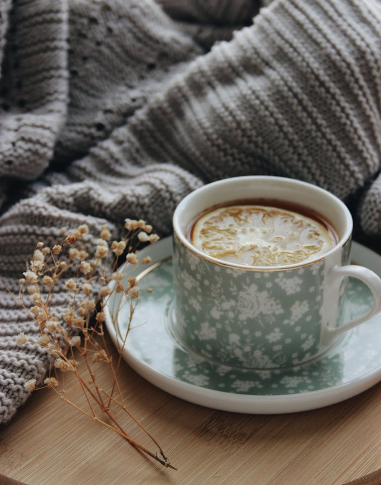 A warm cup of tea with a lemon slice in a floral cup, perfect for a cozy day indoors.